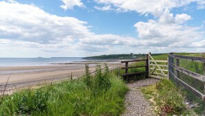 A coastal pathway leading to a beach with a wooden gate and chain-link fence. - Waterford Villa 5 Bed Beach Retreat (Ardmore)