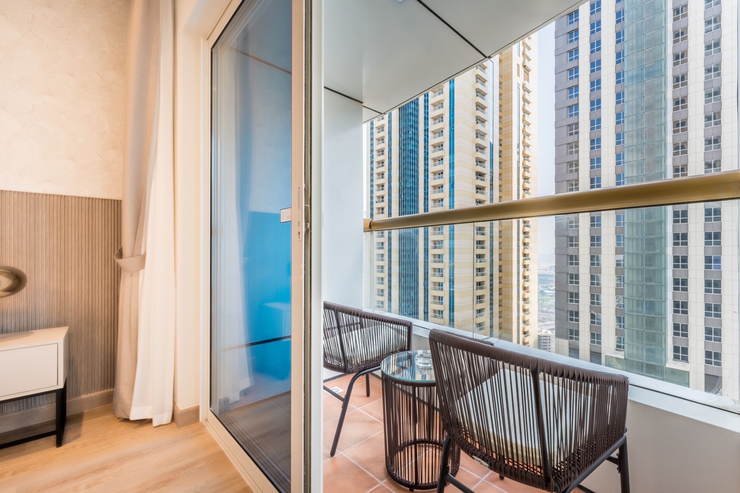 A balcony with a view of high-rise buildings, a glass door, and a small table with chairs.