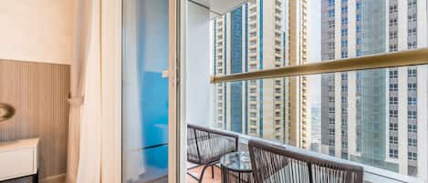 A balcony with a view of high-rise buildings, a glass door, and a small table with chairs.
