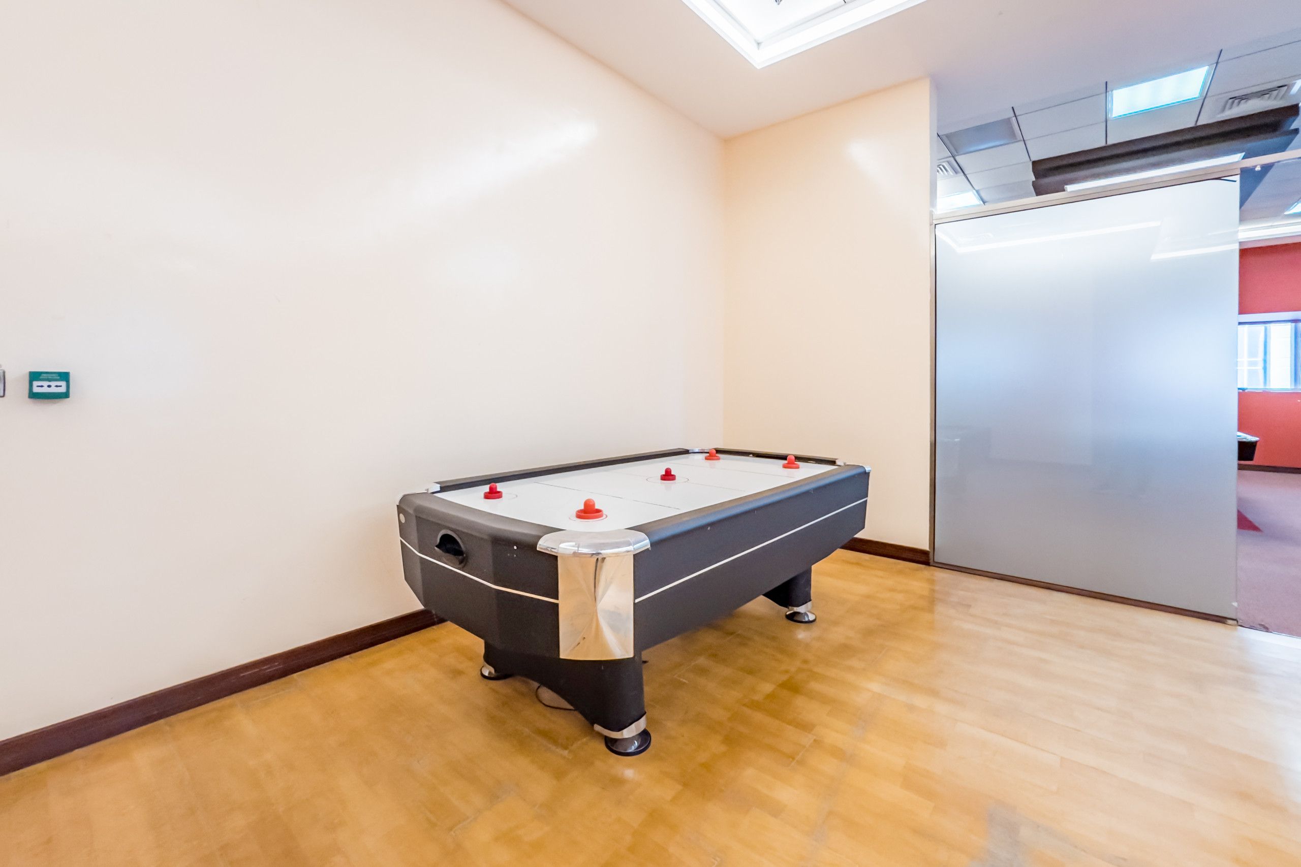 Una mesa de billar en una habitación con suelo de madera y paredes blancas.