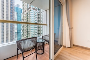 Un balcon avec une porte vitrée, une petite table et deux chaises en osier.