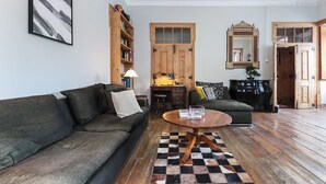 Una sala de estar acogedora con un sofá verde oscuro, una mesa de centro de madera y una alfombra estampada.