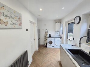 Una cocina moderna con lavadora incorporada, un radiador y un reloj en la pared.