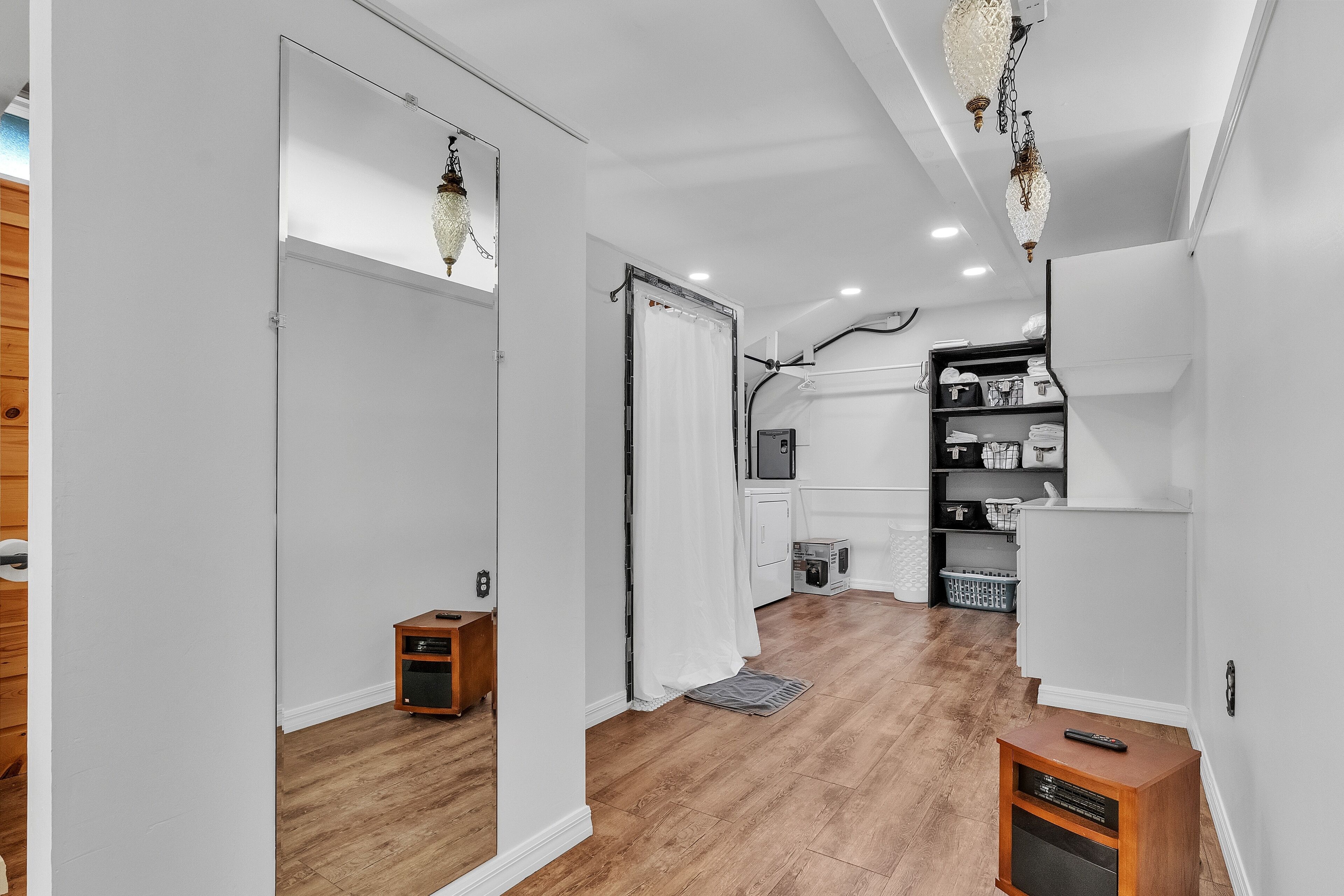 A modern kitchen with white cabinets, a black countertop, and a wooden floor.