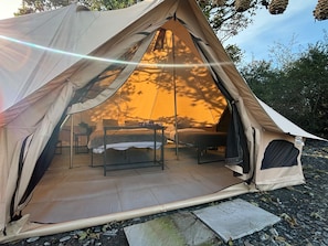 Relax in this well-structured tent with a comfortable bed, table, and seating area.