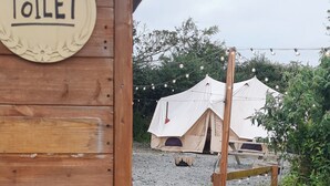 A wooden building with a sign reading "Toilet" and a gravel path leading to a tented area. - Cozy Hot Tent With Log Burner & Hot Tub Right Tent (Gaerwen)