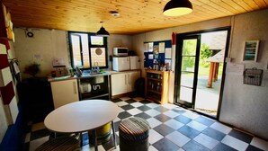 A small kitchen with a checkered floor, a white table, and a microwave. - Cozy Hot Tent With Log Burner & Hot Tub Right Tent (Gaerwen)