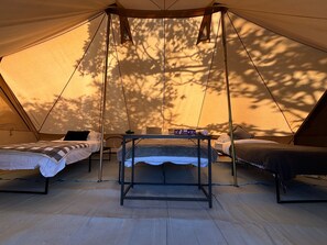 A tent with two beds and a table, set up in a forested area. - Cozy Hot Tent With Log Burner & Hot Tub Right Tent (Gaerwen)
