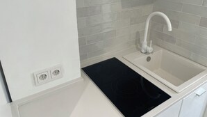 A modern kitchen with a white sink, a Bosch induction cooktop, and grey tiled backsplash. - Little Aventino B&B - Charming bed & breakfast with AC/WiFi in the heart of Rome (Rome)