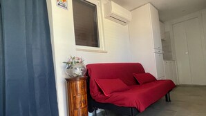A room with a bed, a wooden side table with a vase, a window, and an air conditioning unit. - Little Aventino B&B - Charming bed & breakfast with AC/WiFi in the heart of Rome (Rome)