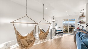 A modern living room with a blue sofa, a hanging chair, and a wooden floor. - Always An Adventure 4 Bedroom Townhouse (St. George)