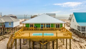 Una casa frente a la playa con terraza de madera y piscina.