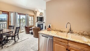 A modern kitchen with a granite countertop, stainless steel sink, and wooden cabinets. - 5959 Hidden River Lodge 2 Bedroom Condo (Keystone)