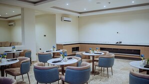 Un comedor moderno con mesas y sillas redondas, unidades de aire acondicionado y un piso de mármol.