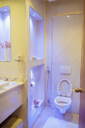 Et badeværelse med toilet, håndvask og bruseområde.
