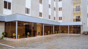 Entrada de hotel con un área exterior cubierta, plantas en macetas y un patio empedrado.