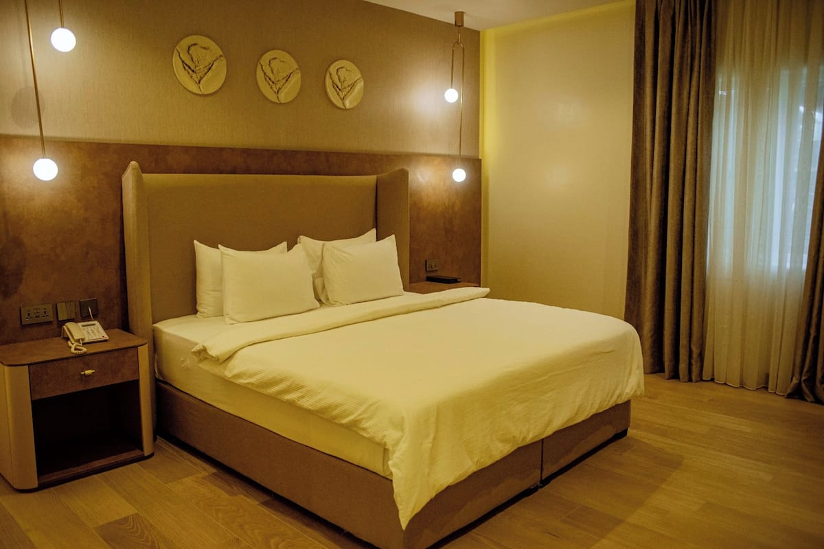 A hotel room with a large bed, bedside tables, a telephone, and wall-mounted lights.