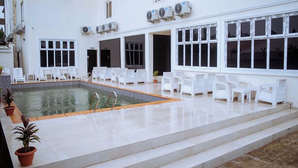 Zona de piscina con sillas blancas y una pileta pequeña.