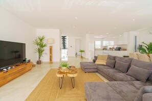 A modern living room with a flat-screen TV, a grey sofa, and a wooden coffee table.