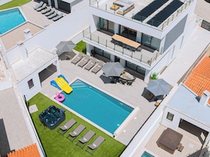 A modern hotel with a rooftop pool, lounge chairs, and a hot tub.