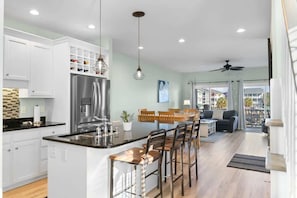 A modern kitchen with a central island, bar stools, and a dining area with a view.