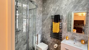 A modern bathroom with a glass-enclosed shower, a toilet, a vanity with a mirror, and a towel rack. - Cozy London Apartment , 2 Minutes to Tube! (London)