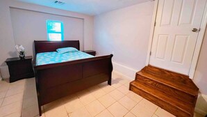 Une chambre à coucher avec un lit, une table de chevet, une fenêtre et une porte.