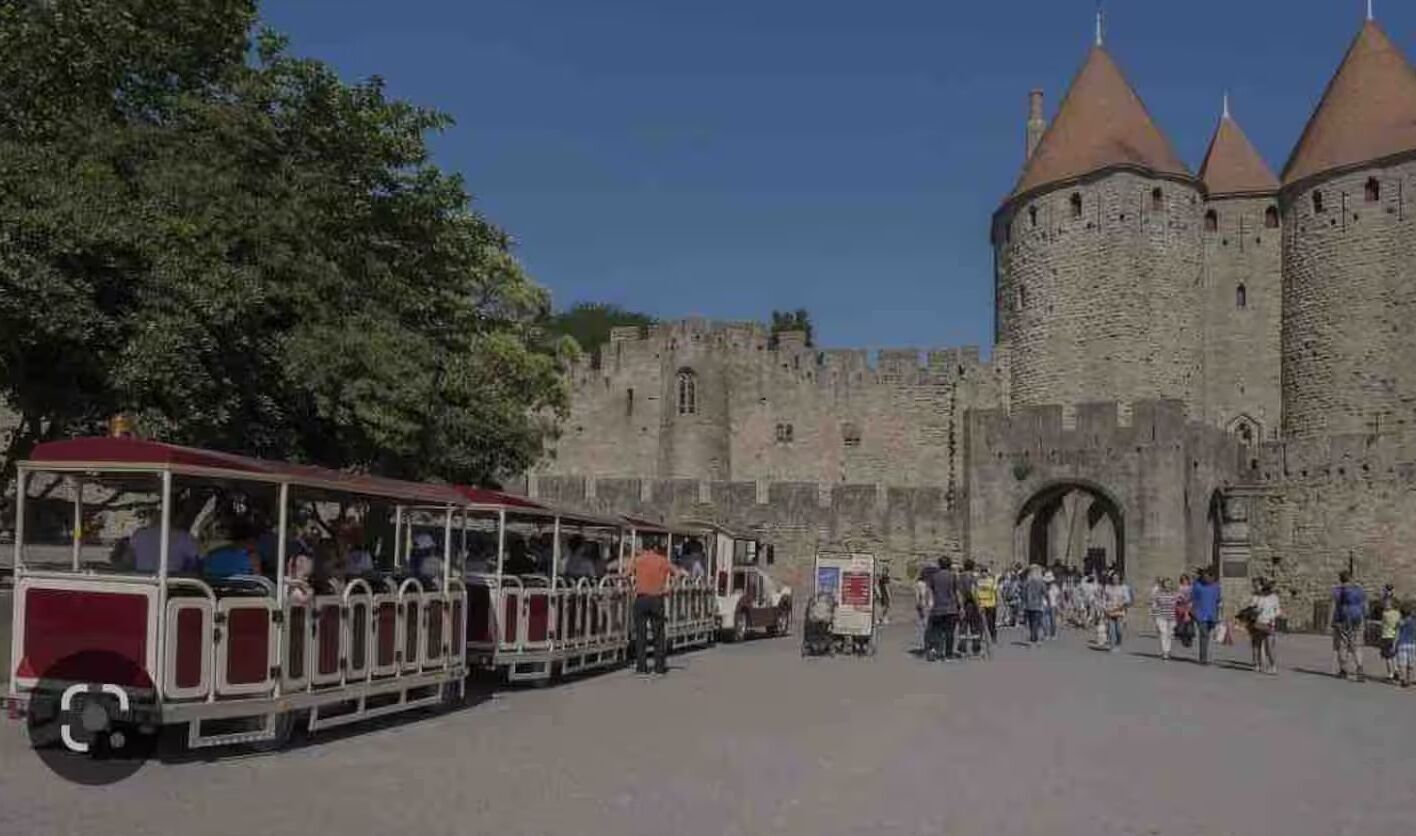 Un château historique doté d’une grande porte d’entrée et d’un tramway devant.