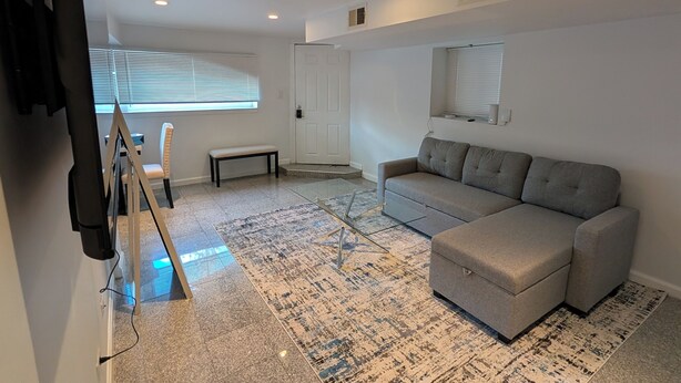 A modern living room with a sectional sofa, a large rug, and a television mounted on the wall. - Comfy 2-bedroom apartment with AC, WiFi in Oak Park (Oak Park)