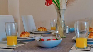 A breakfast setting with croissants, a bowl of strawberries, and glasses of orange juice on a table.