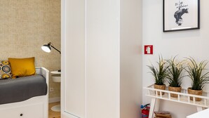 A bedroom with a bed, bedside table, lamp, and a wall with a framed picture. - Belem Design Studio 2 by Homing (Lisbon)