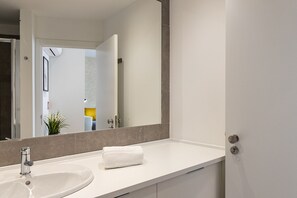 Un baño con un lavamanos blanco, un espejo y una toalla sobre el mostrador.
