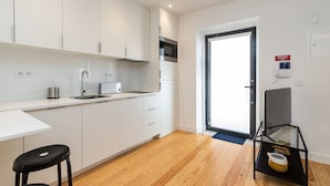 A modern kitchen with white cabinets, a stainless steel microwave, and a black countertop. - Belem Design Studio 2 by Homing (Lisbon)