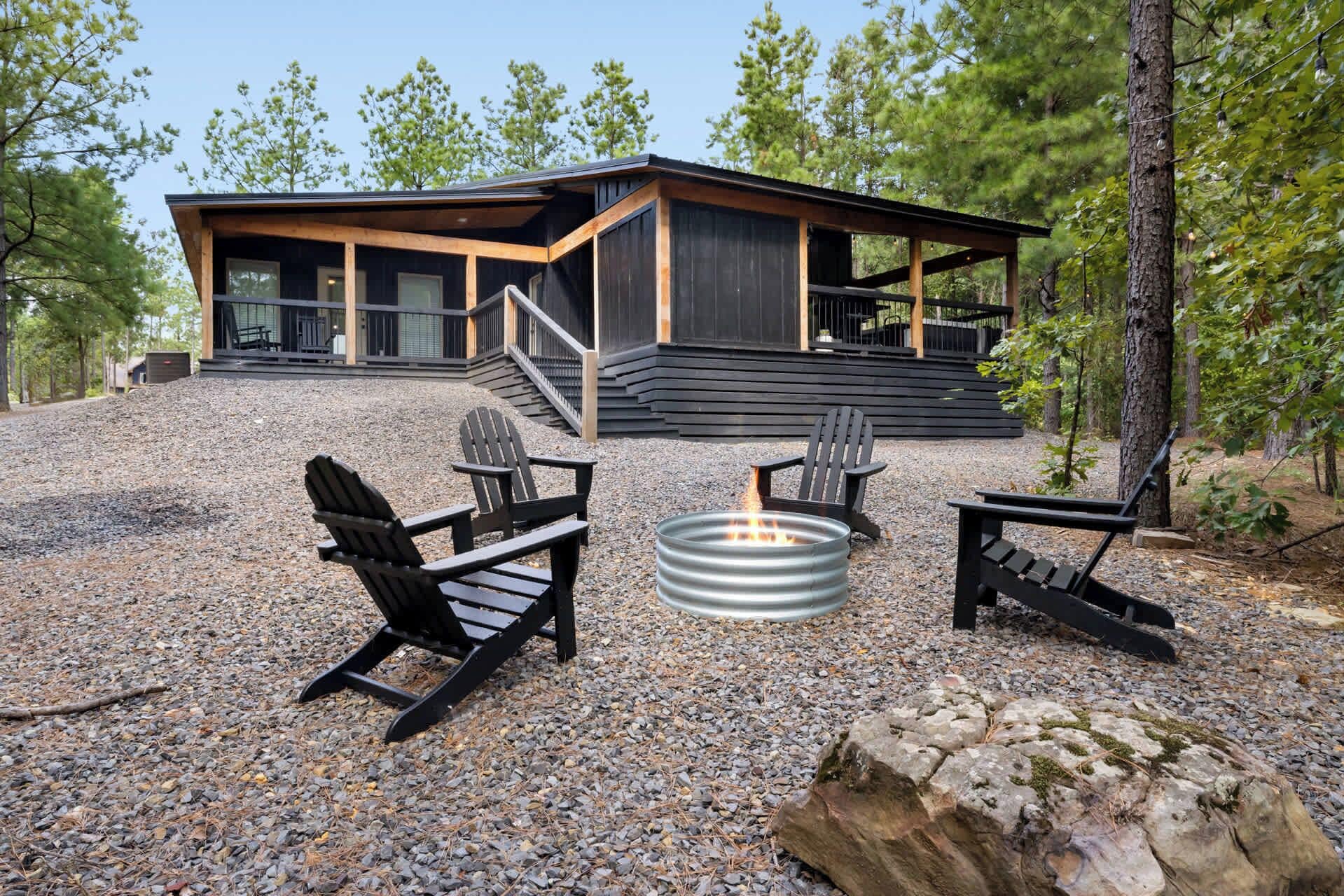 En moderne hytte med en overdækket terrasse, udendørs møbler og et bålsted.