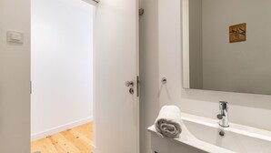 Uma casa de banho com uma pia branca, uma toalha e um espelho.
