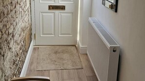 A hallway with a white door, a radiator, and a rug. - Stylish 2-bed House in Stamford Town Centre (Stamford)