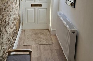 Un pasillo con una puerta blanca, un radiador y una alfombra.