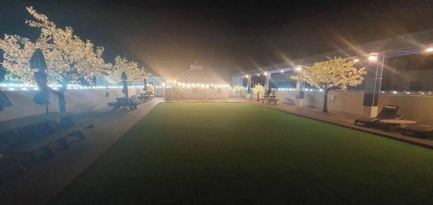 Un espacio al aire libre con césped artificial, asientos y árboles.