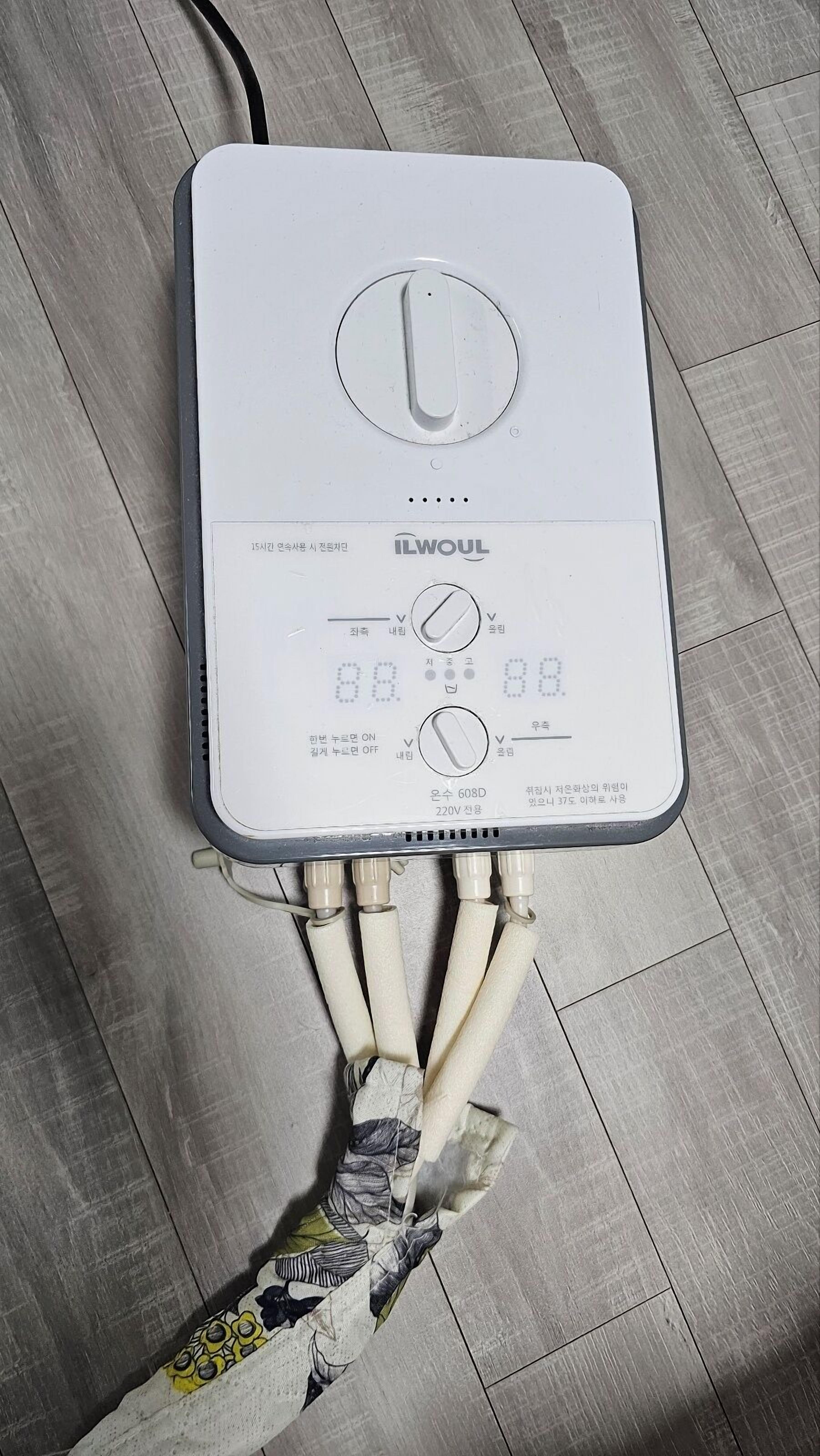 A white electrical device with multiple ports on a wooden floor.