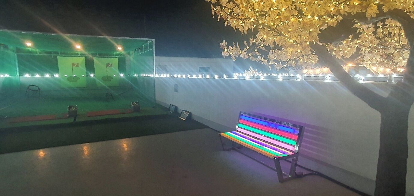 Un espacio al aire libre con un banco, un escenario con luces y un árbol.