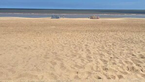 Une vaste plage de sable fin, sous un ciel dégagé.