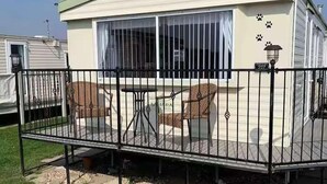 Une maison mobile dotée d’un patio, d’un espace salon couvert et d’une terrasse clôturée.