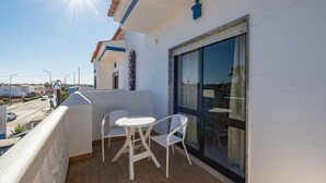 A balcony with two white chairs and a small table, a large window, and a view of the street. - New Sunset Haven in Gale-2br With Big Terrace (Albufeira)