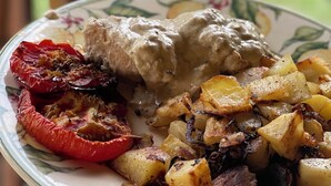 Un plato con un guiso de carne, patatas asadas y pimientos rojos.