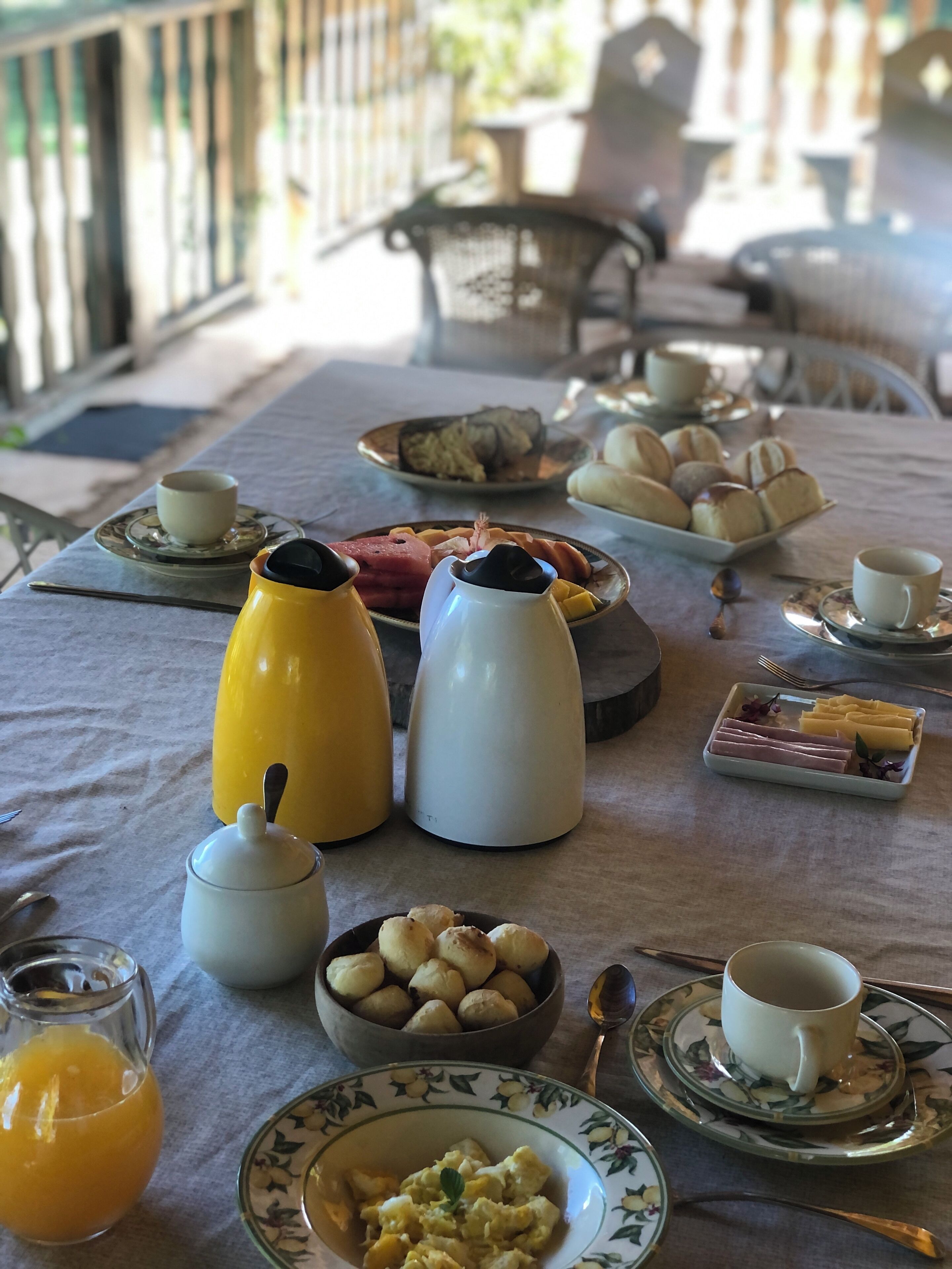 A breakfast table set with various dishes, cups, and a jug of orange juice.