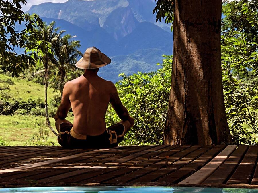 A person meditating by a pool with a mountainous backdrop, labeled "FAZENDA DO FRANCÊS" and "MEDITATION".