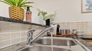 A kitchen sink with running water, a woven basket, and a potted plant. - Tropical Resort Apartment with Pool and Gym Access (Westcourt)