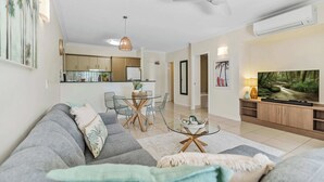 A modern living room with a sofa, TV, and dining area. - Tropical Resort Apartment with Pool and Gym Access (Westcourt)