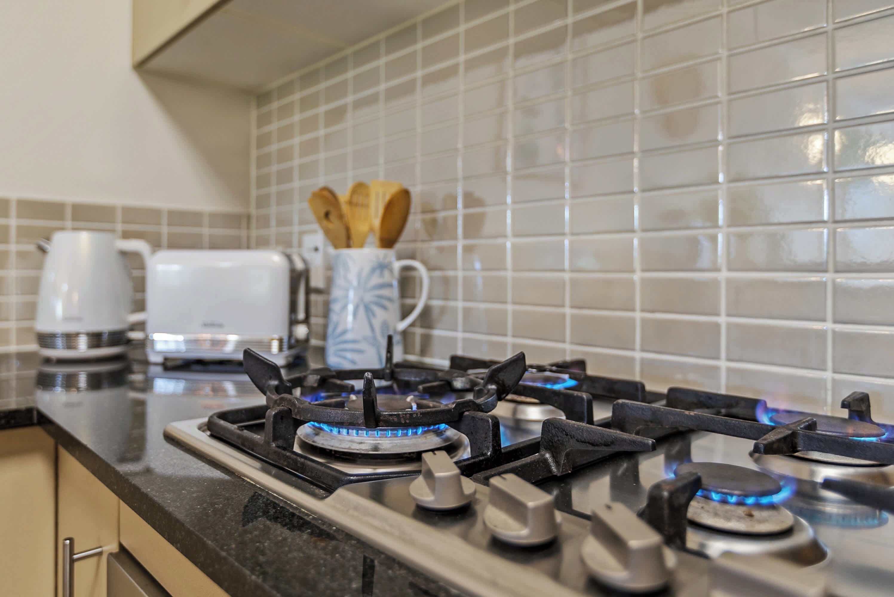 A kitchen with a gas stove, a coffee maker, and a toaster.