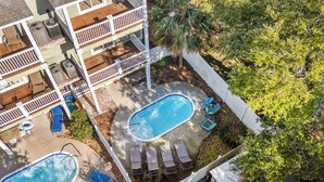 A two-story house with a backyard featuring two swimming pools, lounge chairs, and a wooden deck. - 7th SunDaze w/Private Pool By Beach Star (Surfside Beach)